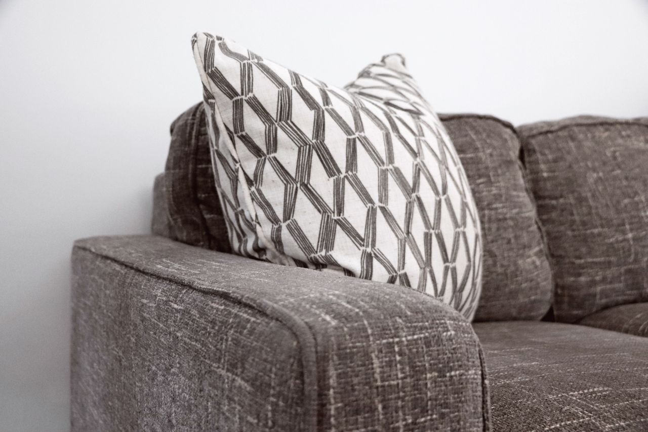 gallery-03 A chic gray sofa paired with a patterned throw pillow brings a refined touch to any living area.